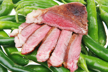 meat steak sliced over green hot chili peppers