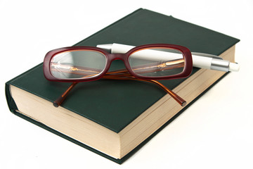 Glasses on book and pen isolated in white