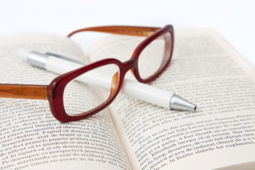 Glasses on book and pen isolated in white