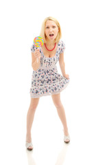 Attractive surprised  blonde with lollipop holding her dress