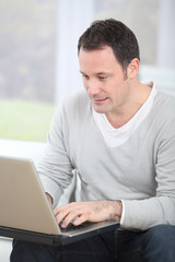 Man sitting in couch using laptop computer
