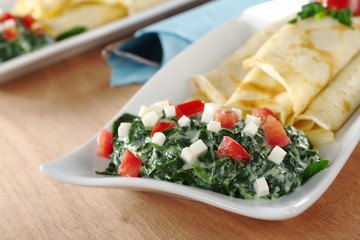 Spinach-tomato-cheese sauce with thin rolled pancakes