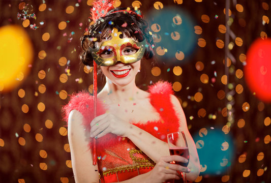 Lady in red dress at the carnival with champagne flute and mask