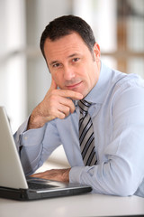 Portrait of businessman in front of laptop computer