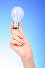 hand with lightbulb on blue background