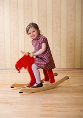 Happy little girl play with toy wooden deer