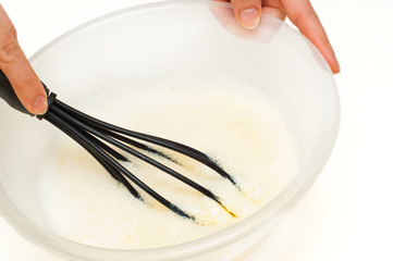whipping dough with a whisk against white background
