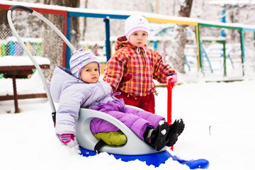 Children playing with sled and spade in snow