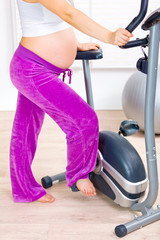 Pregnant female preparing for workout on bicycle. Closeup..