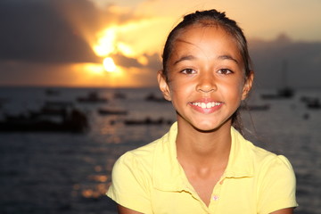 Young mixed race girl sitting by the sea at sunset