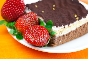 cake on a plate and strawberries lying on the orange fabric