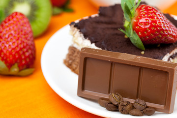 lemon tea,chocolate, kiwi,cake and strawberries lying on the ora