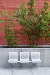 Three metal seats in front of a red brick wall