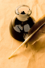 Feather and ink bottle isolated on paper background