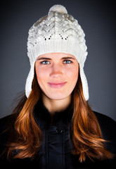 Portrait of the young girl in a winter cap on the dark