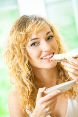 Woman eating crispbread with cheese at home