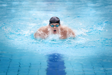 Swimmer in cap breathing performing the butterfly stroke