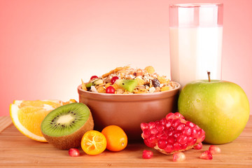 muesli, milk and fruits on red background
