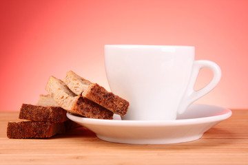 Cup of coffee and rusk on red background
