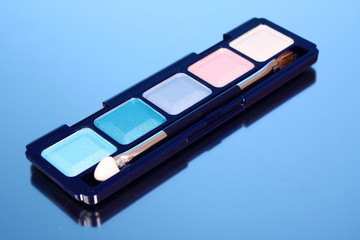 Brush and eye shadows on blue background