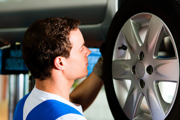 Car mechanic in workshop changing tire