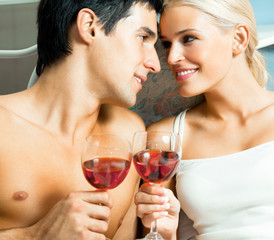 Young happy amorous couple with redwine at bedroom