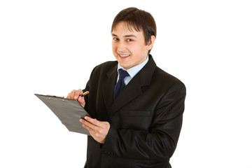 Smiling young businessman making notes in document