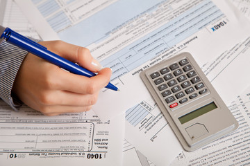 Obraz premium Woman hand filling income tax forms with calculator
