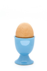 Egg in blue egg cup on white background