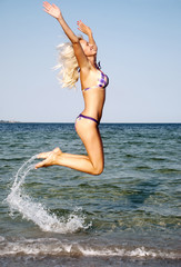 happy young woman jumping in the beach