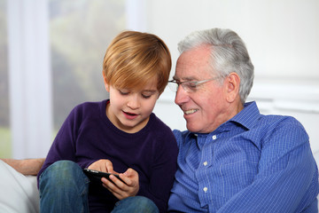 Old man with little boy playing video game on telephone