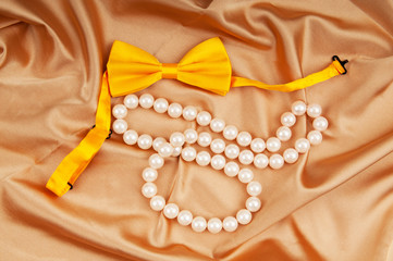 Bow ties and pearl necklace on the satin
