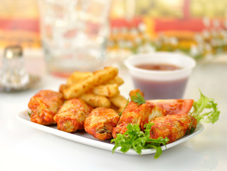 hot chicken wings with fried potatoes and sauce