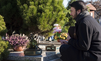 Mourning Man Standing on a Grave at the Cemetery