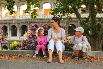young mother, little son and daughter sitting near Colosseum
