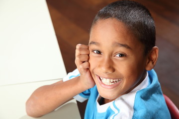 Laughing young school boy 9 sitting to his classroom desk