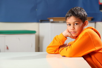 Serious school boy 10 deep thought in classroom