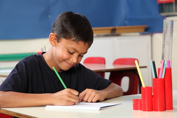 Young school boy 10 writing at his classroom desk