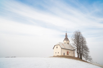 Small church on snowy hill. Slovenia, Skofja Loka area - 29210775