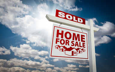 White and Red Sold Home for Sale Real Estate Sign Over Clouds an