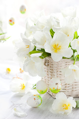 white tulips in a basket and easter colored eggs