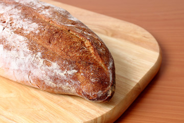 una barra de pan fresco tostado sobre plato de madera