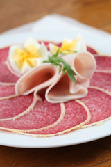 Salami with parmesan crust on a plate with ham and eggs