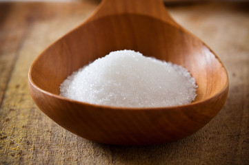 Pile of white sugar in wooden spoon