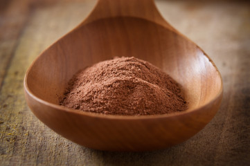 Pile of cocoa powder in wooden spoon