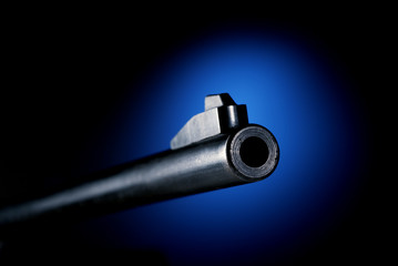 Gun barrel at angle back lit by blue spot