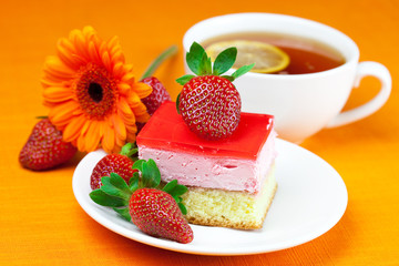 gerbera, lemon tea, cake and strawberries lying on the orange fa