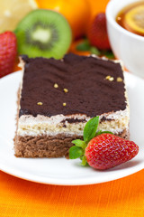 lemon tea, kiwi,cake and strawberries lying on the orange fabric