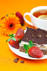 gerbera, lemon tea, cake and strawberries lying on the orange fa
