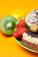 cake, chocolate candy, tangerine, kiwi and strawberries on the o